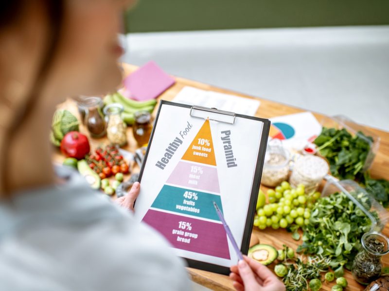 Holding schematic meal plan for diet with various healthy products on the background