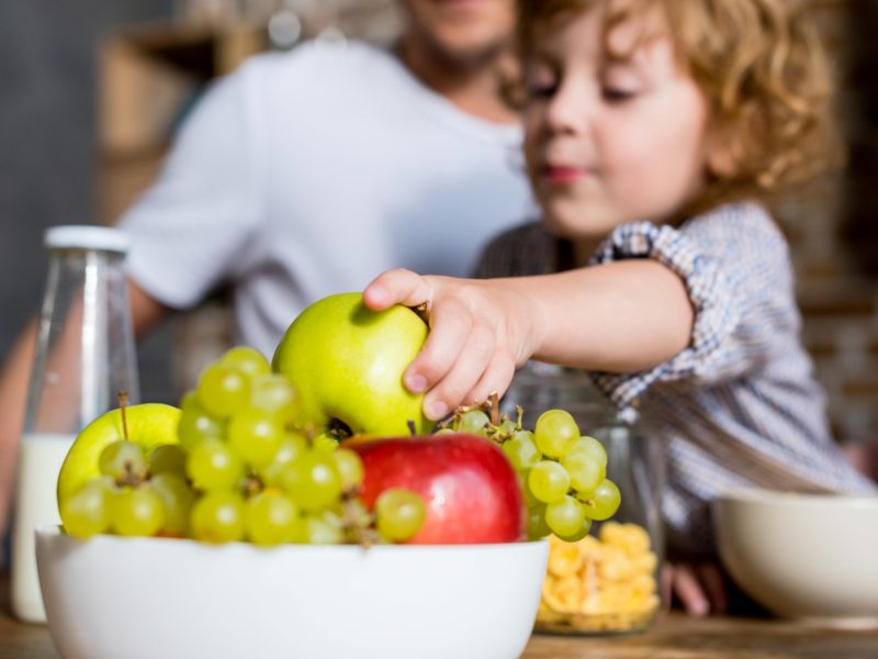 close-up view of cute little boy eating fresh fruits at breakfast